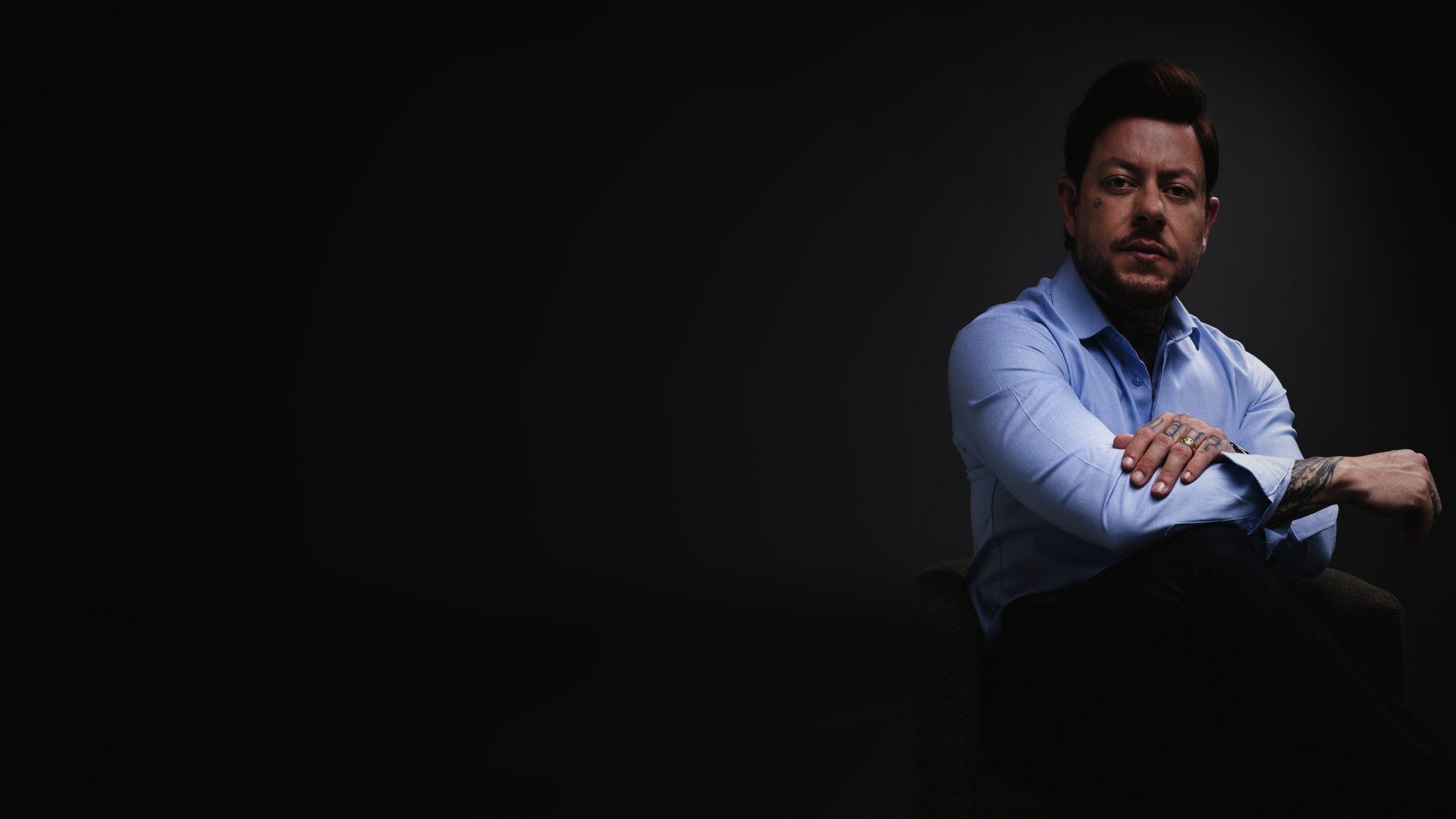 Greg Pàz, retrato em estúdio escuro, braços cruzados