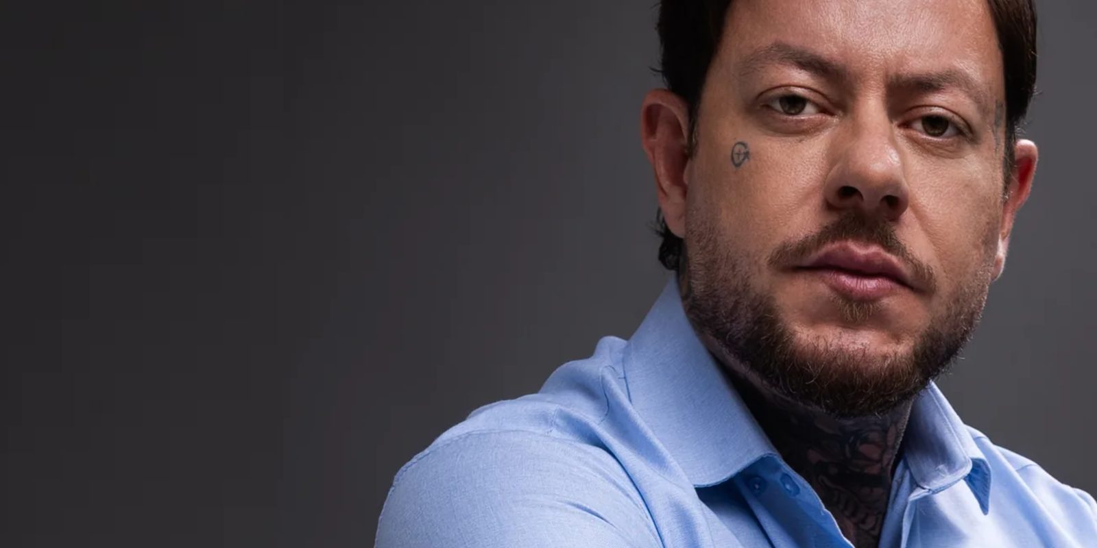 Greg Pàz em retrato de estúdio, olhando diretamente para a câmera.